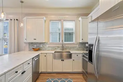 a kitchen with white cabinets and a stainless steel refrigerator at Arrabella - Gulf Views with Deck & Community Pool in Santa Rosa Beach