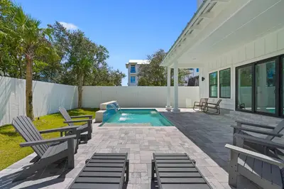 a patio with chairs and a swimming pool at Big Gus - Huge Home Near the Beach with Gulf Views & Secluded Pool Area in Rosemary Beach