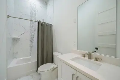 a white bathroom with a toilet and a sink at Big Gus - Huge Home Near the Beach with Gulf Views & Secluded Pool Area in Rosemary Beach