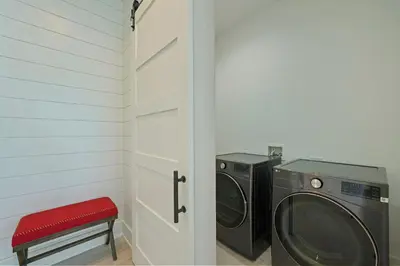 a laundry room with a washing machine and a red stool at Big Gus - Huge Home Near the Beach with Gulf Views & Secluded Pool Area in Rosemary Beach