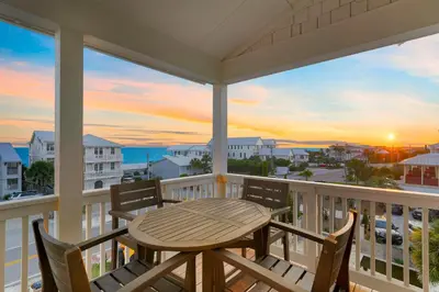 a table and chairs on a balcony with a view of the ocean at Big Gus - Huge Home Near the Beach with Gulf Views & Secluded Pool Area in Rosemary Beach