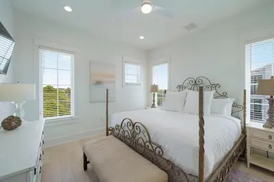 a bedroom with a bed and a desk and windows at Big Gus - Huge Home Near the Beach with Gulf Views & Secluded Pool Area in Rosemary Beach