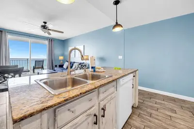 a kitchen with a sink and a living room at Sterling Reef 505 by Emerald Coast Retreats in Panama City Beach