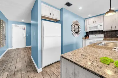 a kitchen with white appliances and blue walls at Sterling Reef 505 by Emerald Coast Retreats in Panama City Beach