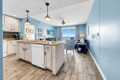 a kitchen with blue walls and white cabinets and a table at Sterling Reef 505 by Emerald Coast Retreats in Panama City Beach