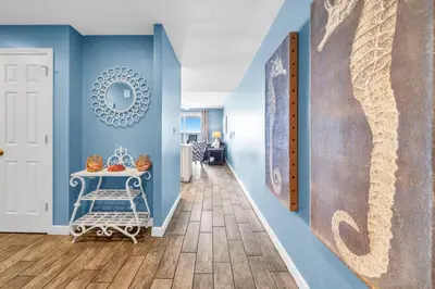 a hallway with blue walls and a table and a mirror at Sterling Reef 505 by Emerald Coast Retreats in Panama City Beach