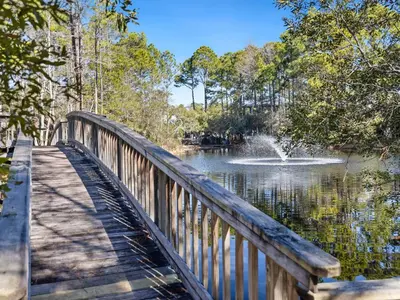a wooden bridge over a pond with a fountain at Cassine Gardens #270 - The Getaway in Santa Rosa Beach