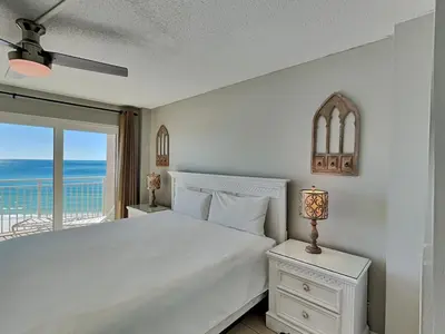 a bedroom with a white bed with a view of the ocean at Dunes of Panama #D705 in Panama City Beach