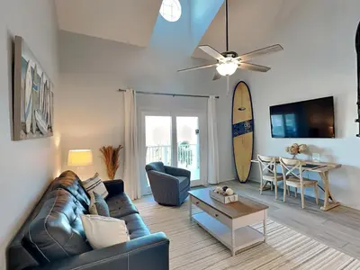 a living room with a couch and a table and a surfboard at Treasure Cove #D308 - Paradise City in Panama City Beach
