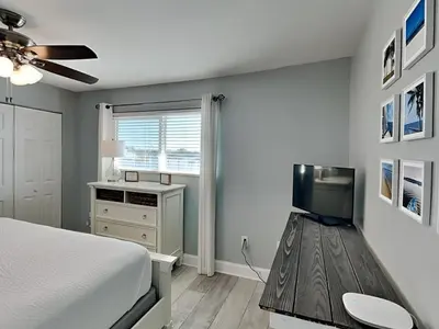 a bedroom with a bed and a television on a wooden floor at Treasure Cove #D308 - Paradise City in Panama City Beach