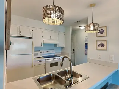 a kitchen with white cabinets and a sink and two lights at Treasure Cove #D308 - Paradise City in Panama City Beach
