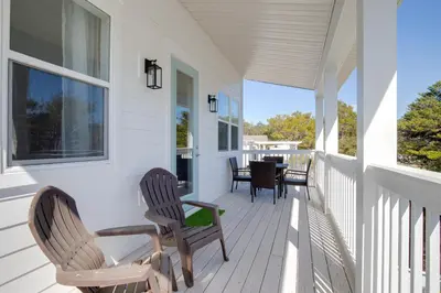 a porch with chairs and a table on it at Seacrest Paradise Spacious 4 bedroom retreat in Inlet Beach, perfect for 13 guests in Inlet Beach