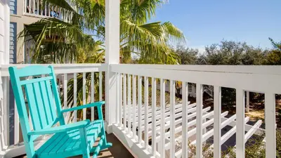 a blue rocking chair on a porch with a palm tree at Experience luxury at Doctor in Inlet Beach