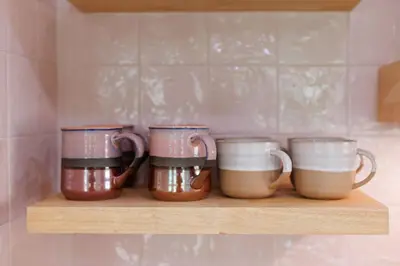 four coffee mugs sitting on a shelf in a kitchen at Sol Haus Stylish Coastal Retreat 3 Blocks to Beach Screened Porch Fast Wi Fi in Panama City Beach
