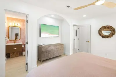a bedroom with a bed and a sink and a mirror at Sol Haus Stylish Coastal Retreat 3 Blocks to Beach Screened Porch Fast Wi Fi in Panama City Beach