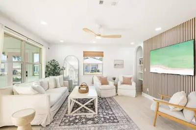 a living room with a white couch and a tv at Sol Haus Stylish Coastal Retreat 3 Blocks to Beach Screened Porch Fast Wi Fi in Panama City Beach