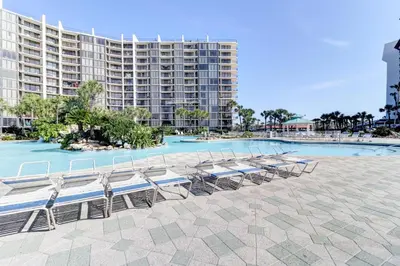 a group of tables and chairs in front of a large building at Billie Jean’s Bungalow! Cozy Edgewater Condo w/ Resort Amenities, Sleeps 6 in Panama City Beach