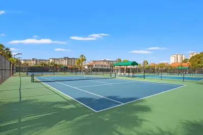 a tennis court with two tennis courts at Billie Jean’s Bungalow! Cozy Edgewater Condo w/ Resort Amenities, Sleeps 6 in Panama City Beach