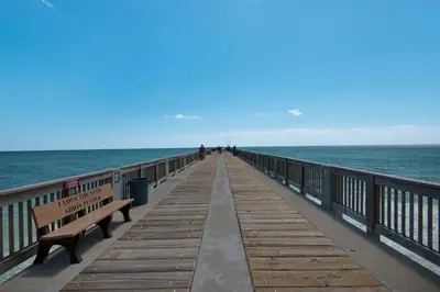 a wooden pier with benches and the ocean at Sunset Cove: Charming 3BR/3BA Beach House Sleeps 8 with Sunsets & Serenity in Panama City Beach
