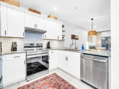 a kitchen with white cabinets and stainless steel appliances at Heron's Watch Way 1102 in Santa Rosa Beach