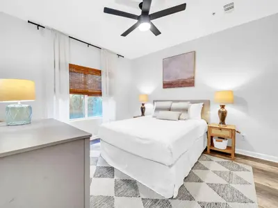 a white bedroom with a bed and a table at Heron's Watch Way 1102 in Santa Rosa Beach