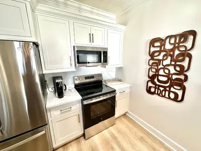 a kitchen with white cabinets and a stainless steel refrigerator at Ocean Reef 1002 in Panama City Beach