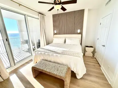 a bedroom with a bed and a balcony at Ocean Reef 1002 in Panama City Beach