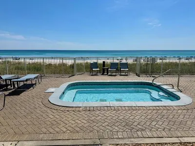 a small swimming pool with chairs and the beach at Ocean Reef 1002 in Panama City Beach