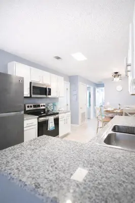 a kitchen with white cabinets and a black refrigerator at WALK TO BEACH Perfect Family Getaway Sleep 6 in Panama City Beach