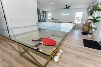 a glass table with a ping pong racket and balls at The Gathering Place by Travel Life Vacations in Santa Rosa Beach