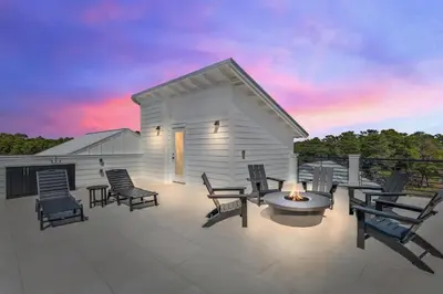 a patio with chairs and a fire pit and a building at The Gathering Place by Travel Life Vacations in Santa Rosa Beach
