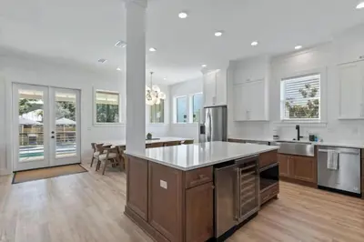 a large kitchen with white walls and wooden flooring at The Gathering Place by Travel Life Vacations in Santa Rosa Beach