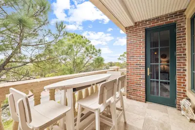 a patio with a table and chairs on a balcony at The Magnolia by 30A Escapes in Rosemary Beach