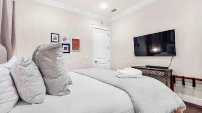 a white bedroom with a bed and a flat screen tv at Sea Breeze on 30A in Seacrest