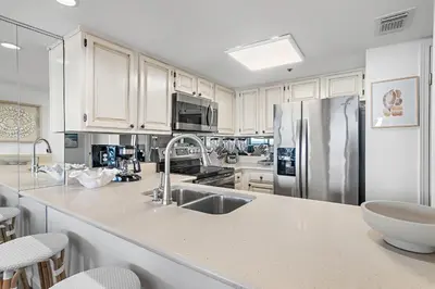 a kitchen with white cabinets and a stainless steel refrigerator at Be Still 30A in Santa Rosa Beach