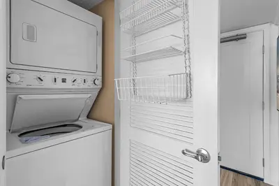 a white refrigerator with a washer and dryer next to a door at Be Still 30A in Santa Rosa Beach