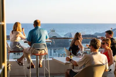 a group of people sitting at tables on a balcony overlooking the ocean at Be Still 30A in Santa Rosa Beach