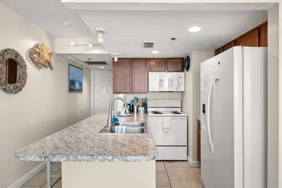 a kitchen with a sink and a white refrigerator at Amazing Gulf Views! Resort! Beach Chair Service by Dolce Vita Getaways PCB in Panama City Beach