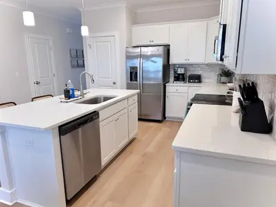 a kitchen with white cabinets and a stainless steel refrigerator at Coastal Retreat, 1 Mile to Beach, Pool & Golf Cart in Panama City Beach