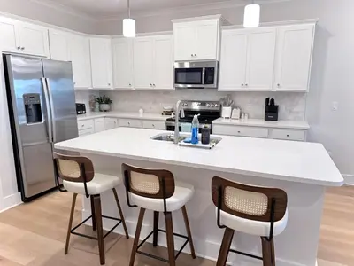a kitchen with white cabinets and a large island with bar stools at Coastal Retreat, 1 Mile to Beach, Pool & Golf Cart in Panama City Beach