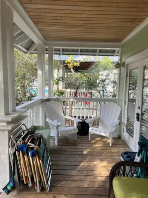 a porch with two chairs and a table with baseball bats at Glory Days 30A - Pool, Bikes & Close Beach Access in Inlet Beach