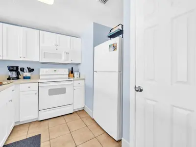 a kitchen with white cabinets and a white refrigerator at Majestic Beach Towers 1-1906 in Panama City Beach