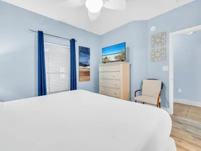 a bedroom with blue walls and a bed and a chair at Majestic Beach Towers 1-1906 in Panama City Beach