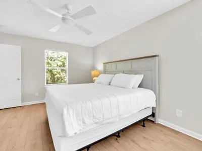 a white bedroom with a large bed and a window at Barefoot Villa in Panama City Beach