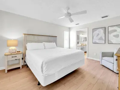 a white bedroom with a large bed and a table at Barefoot Villa in Panama City Beach
