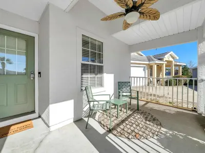 a porch with a green door and a table and chairs at Barefoot Villa in Panama City Beach