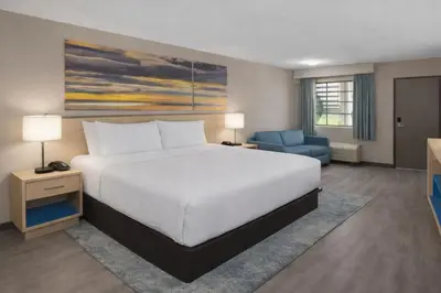 a bedroom with a large bed and a blue chair at The Barefoot Hotel in Panama City Beach