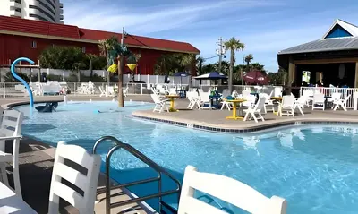a pool at a resort with white chairs and tables at The Barefoot Hotel in Panama City Beach