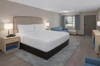 a bedroom with a large white bed and blue chairs at The Barefoot Hotel in Panama City Beach