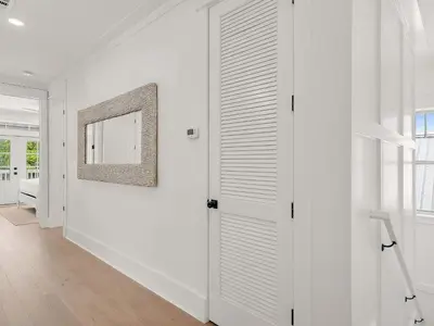 a white hallway with a door and a mirror at Elegant 5BR 30A Home w Hot tub & Pool in Santa Rosa Beach